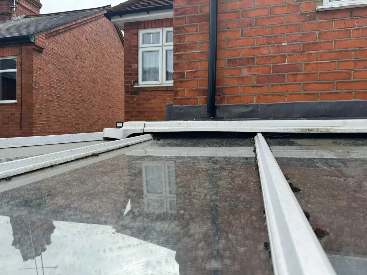 Old glass lean-to conservatory roof seen from above against a brick wall