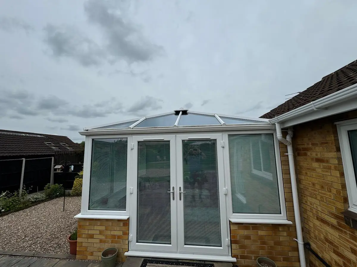 White conservatory with a new grey insulated panel roof on the back of a bungalow