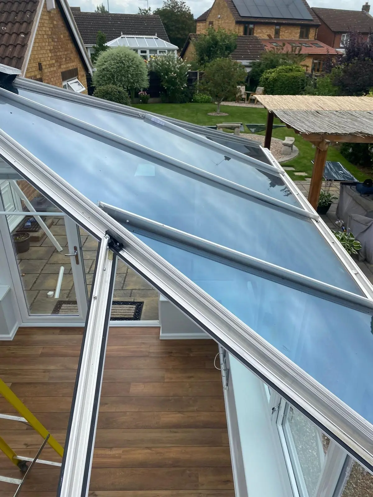 Grey insulated panels being fitted alongside the remaining glass on a conservatory roof