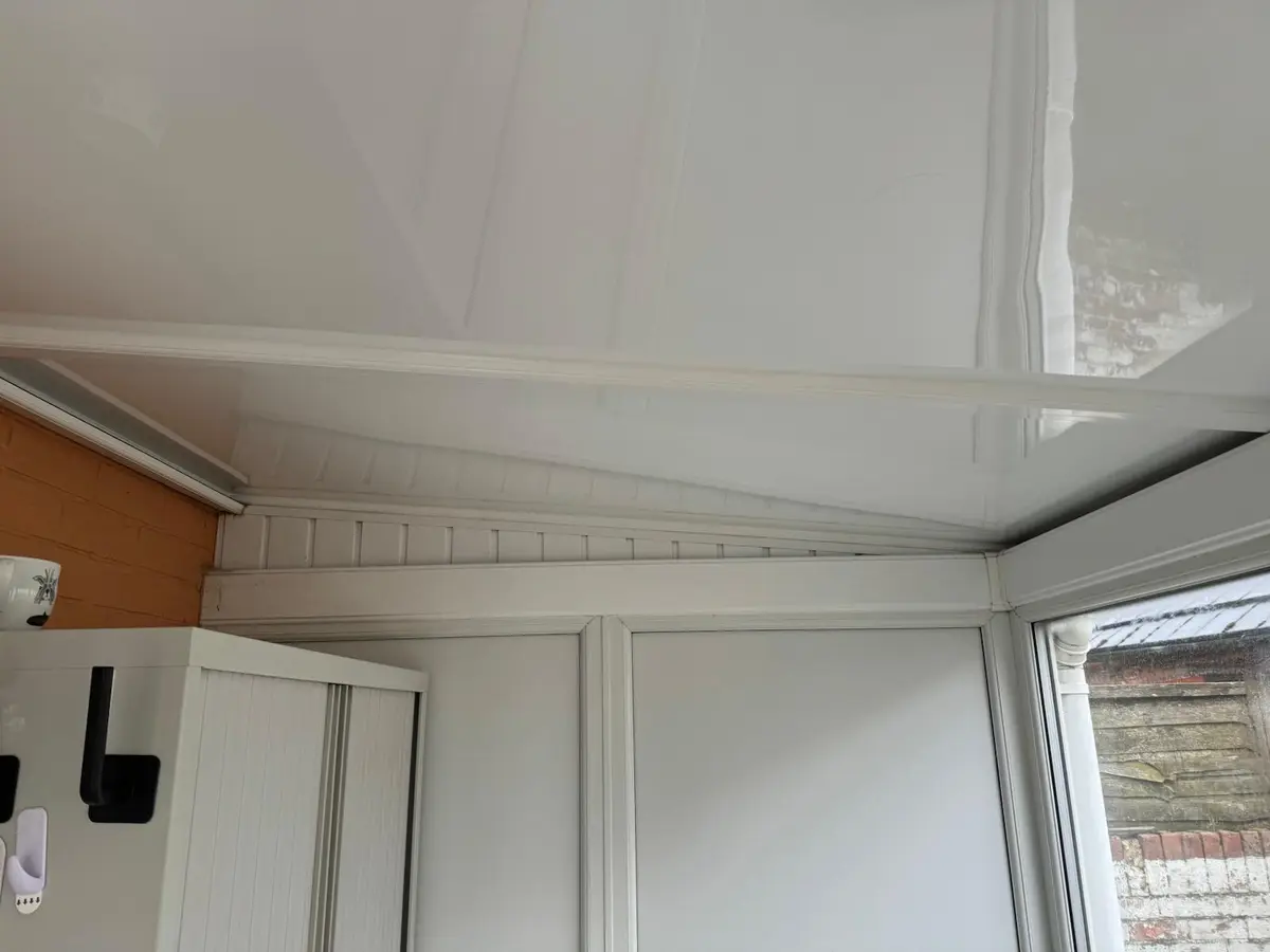 Smooth white insulated panel ceiling inside a small lean-to conservatory
