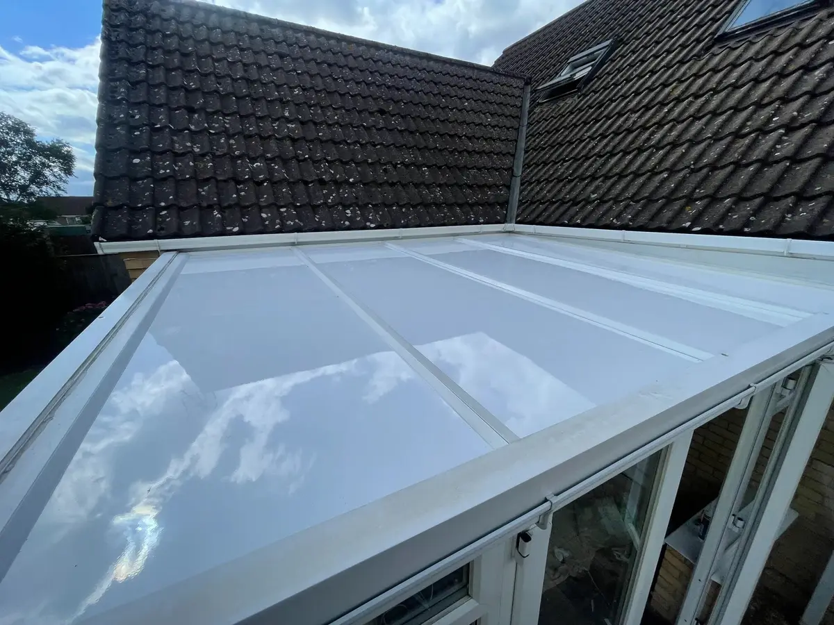 High view along a white insulated panel lean-to roof beside a pitched house roof