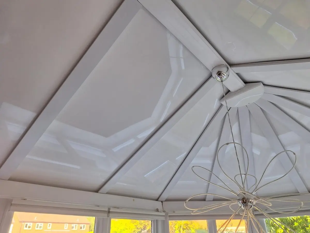 Looking up at a white panel roof hub and pendant light in a conservatory