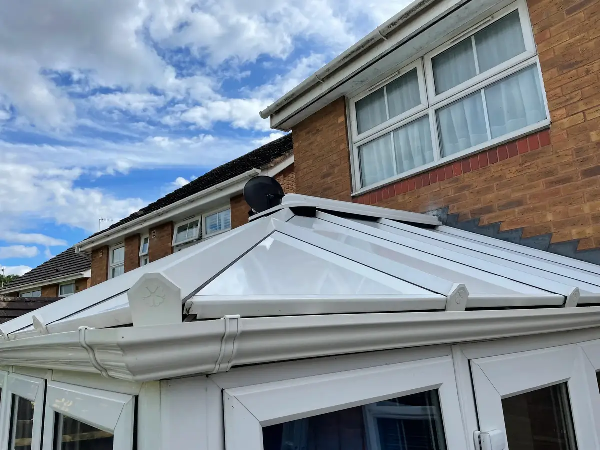 Close view of white insulated roof panels, glazing bar end caps and new guttering on a conservatory