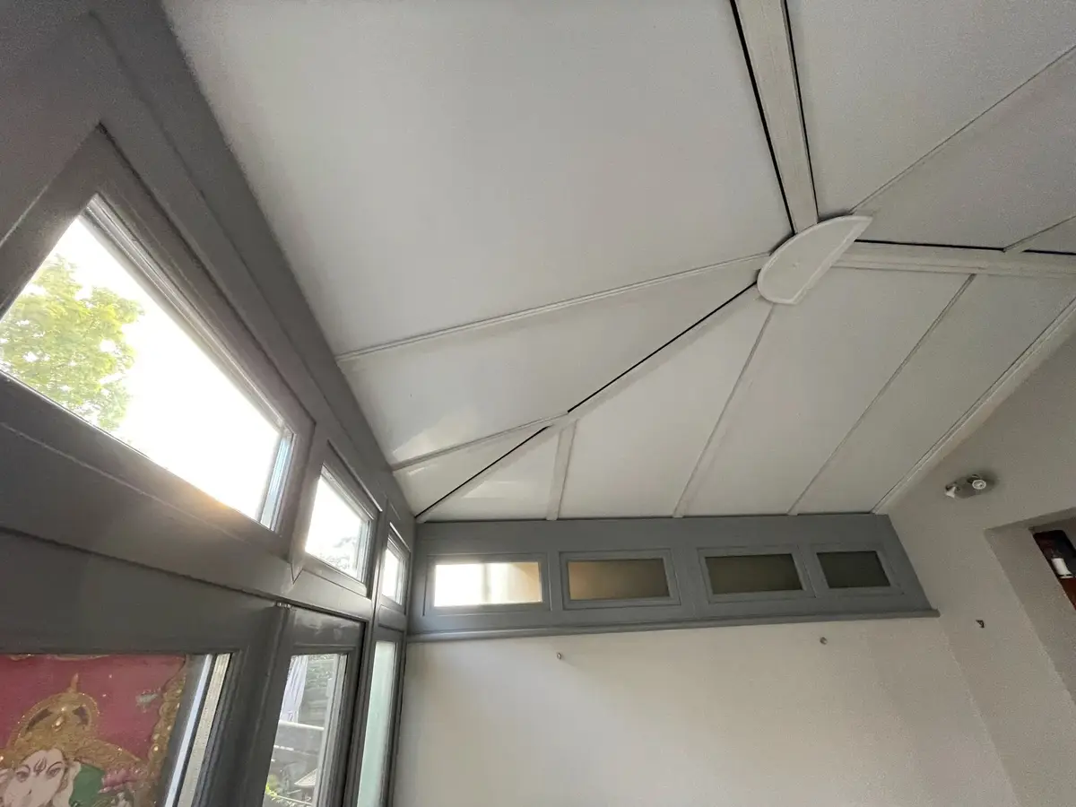 White insulated roof panels meeting at the central hub above grey transom windows
