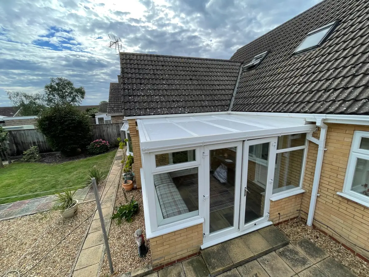 Lean-to conservatory with a white panel roof overlooking a patio and lawn