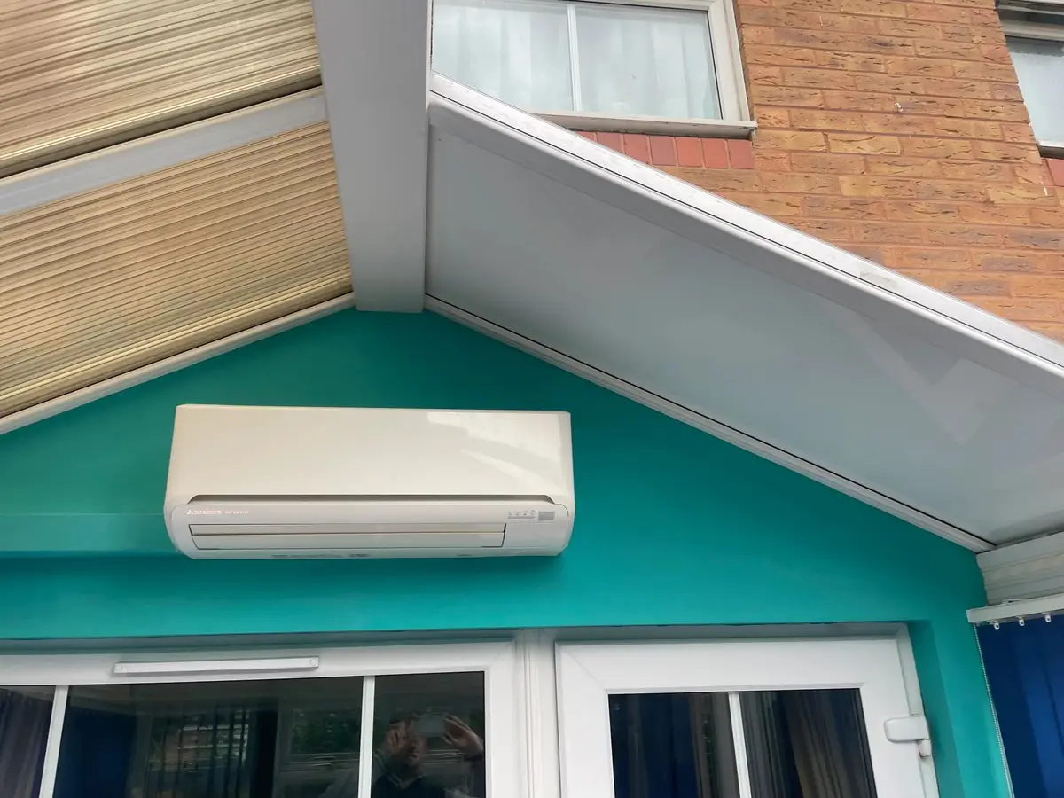 Mid-installation view inside a conservatory: new white insulated panels on one slope, old polycarbonate on the other