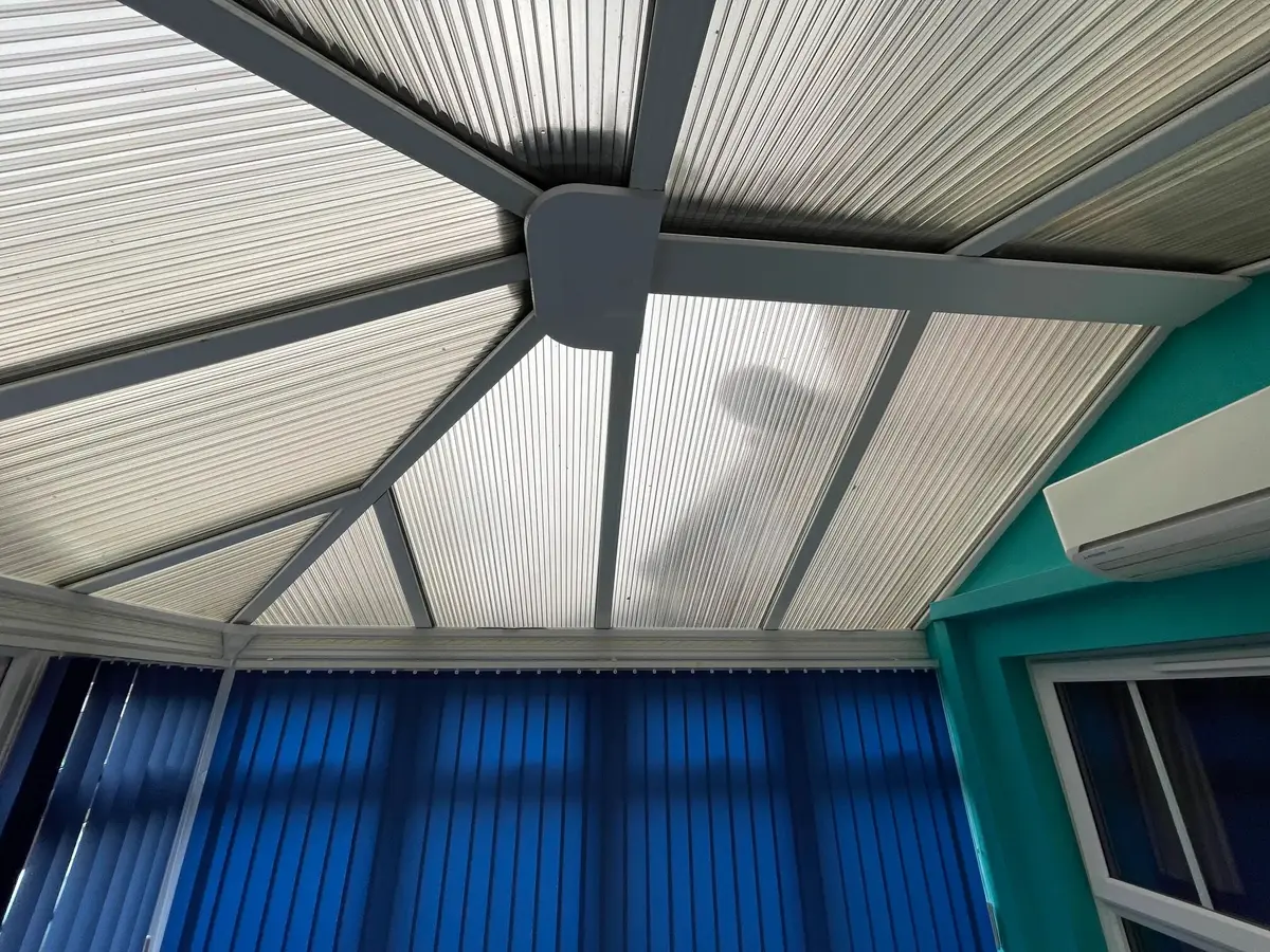 Ribbed polycarbonate roof sheets inside a conservatory with teal walls and blue blinds