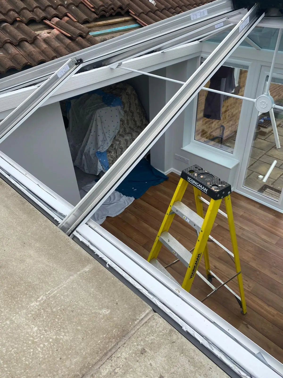 Conservatory roof frame opened up during installation, with a stepladder inside