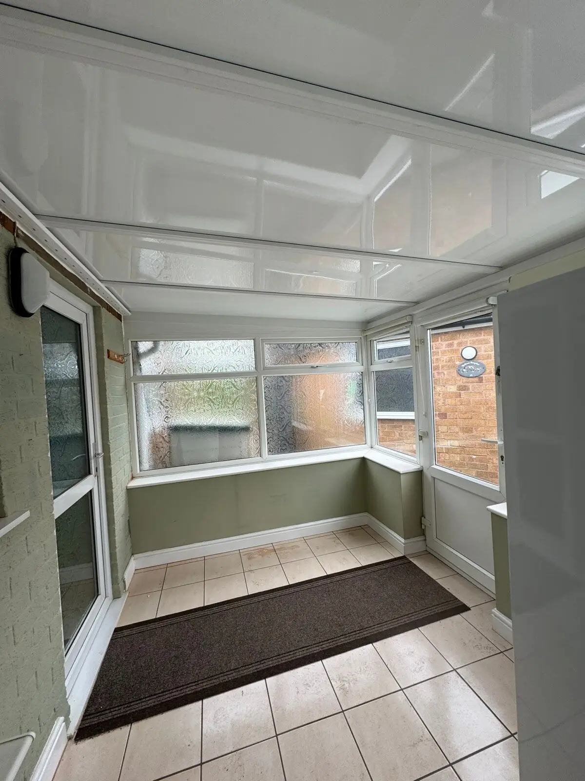 Small lean-to conservatory with a new white panel roof and a ceramic floor