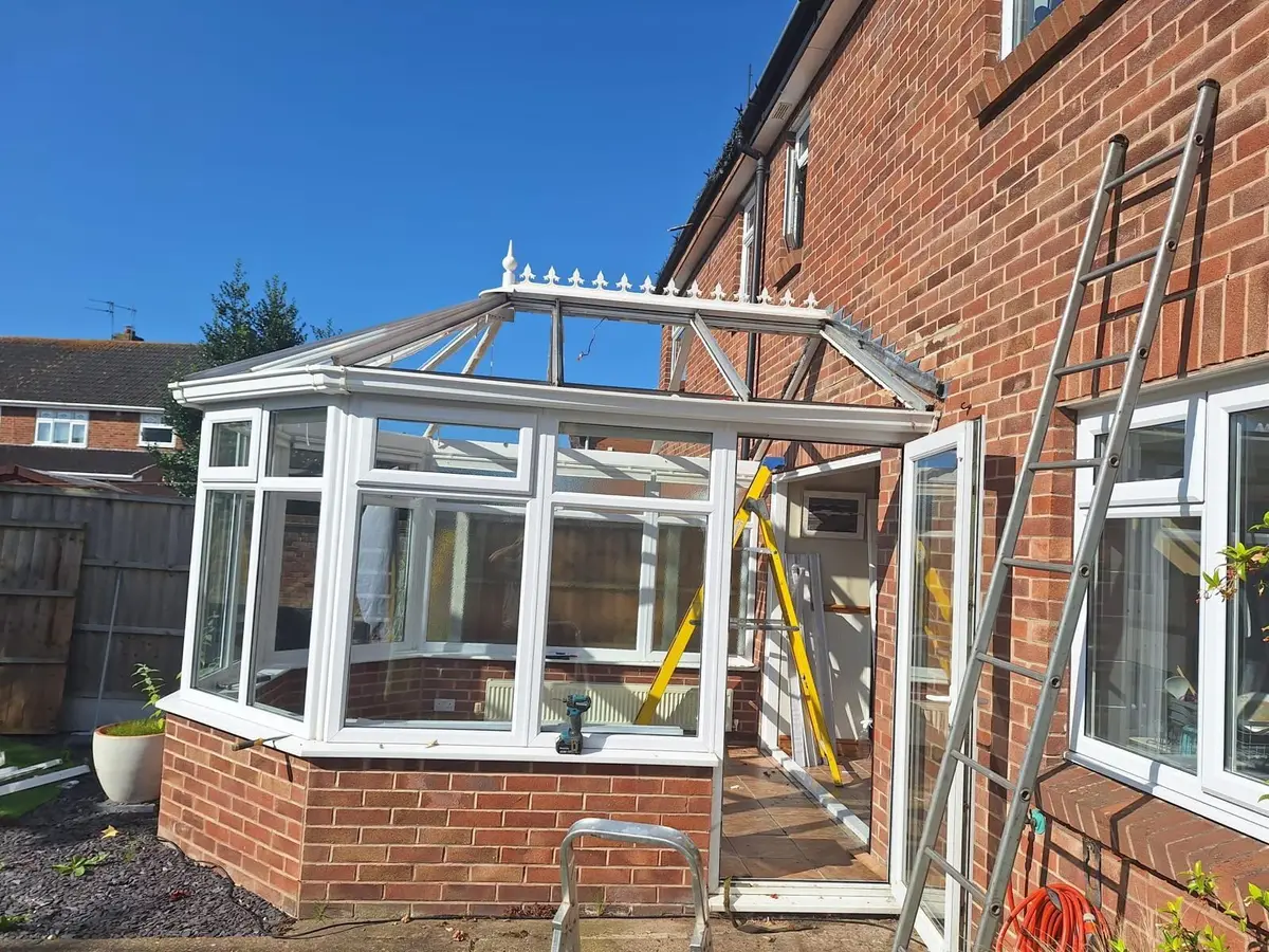 Victorian conservatory with its roof stripped back to the frame and a ladder alongside during installation