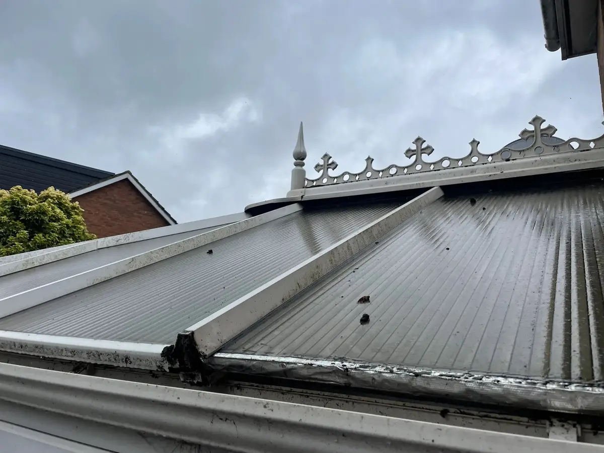 Close view of weathered polycarbonate roof sheets, glazing bars and ridge cresting on a Victorian conservatory