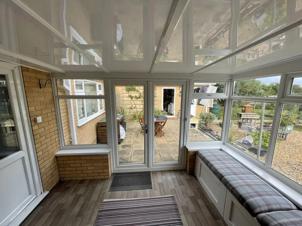 Conservatory with built-in window seats and a glossy white insulated panel ceiling